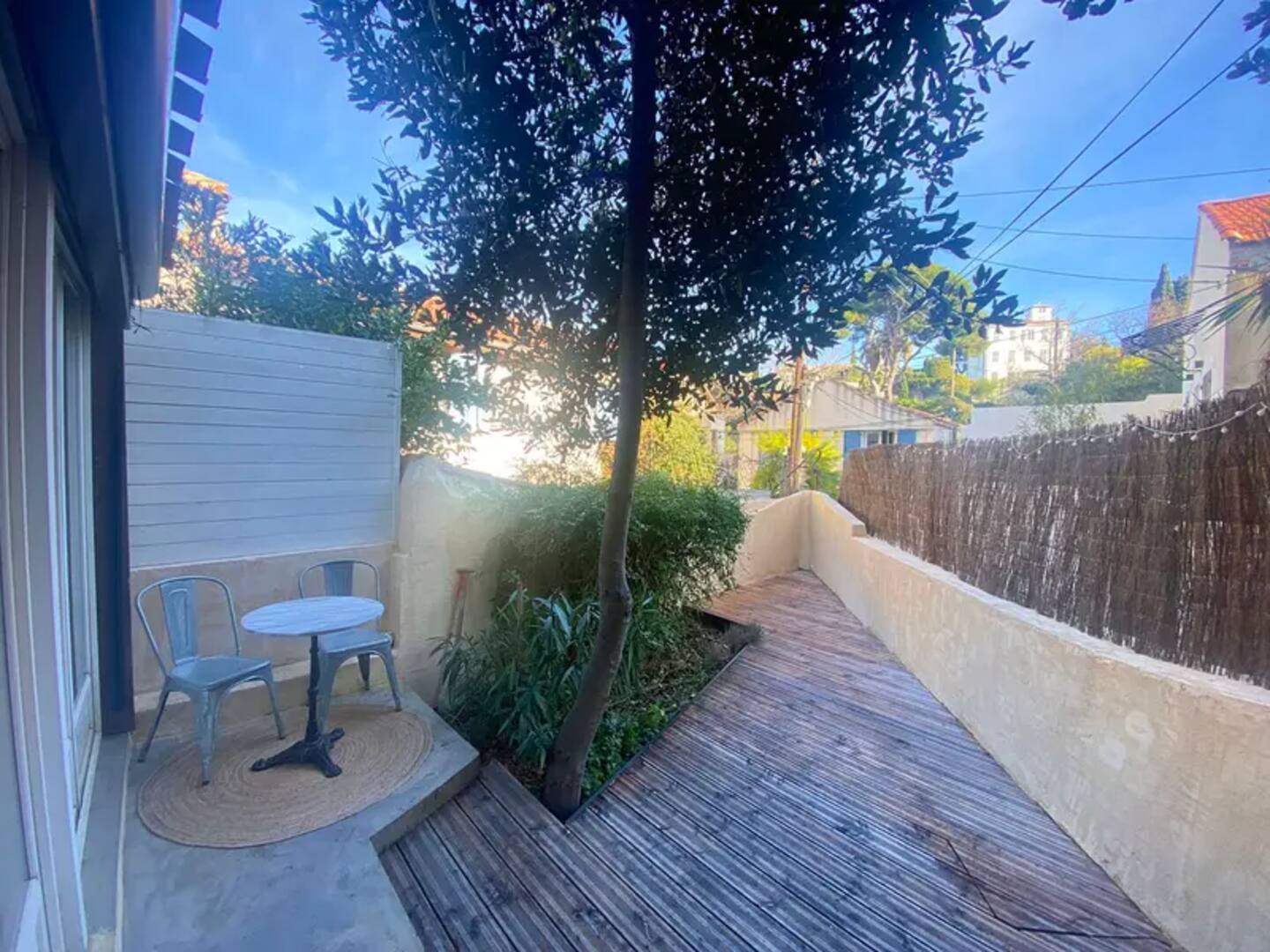 Terrasse privée avec table, chaises et végétation